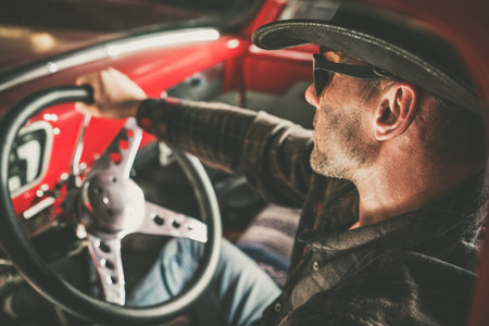 Caucasian American Cowboy Behind Vintage Classic Pickup Wheel. American West Theme.の写真素材