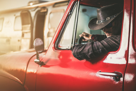 Middle Aged Caucasian Cowboy in a Classic Pickup Truck Next to His Travel Trailerの写真素材