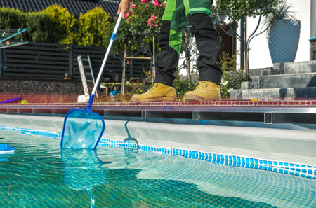 Poolside Maintenance Worker Cleaning Water Surface with a Net. Keeping Swimming Pool Clean.の写真素材