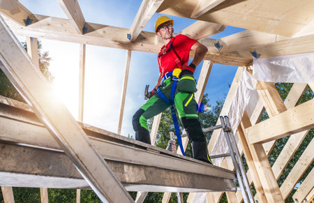 Caucasian Construction Site Worker in His 40s Building Wooden House Roof Framing. Working From...