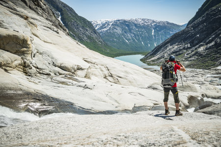 Caucasian Hiking Tourist in Norwegian Glacial Landscape. Summer Norwegian Trails.の写真素材
