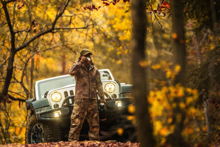 Caucasian Hunter Drinking a Coffee From His flask During Hunting Day. AWD Vehicle in the Background