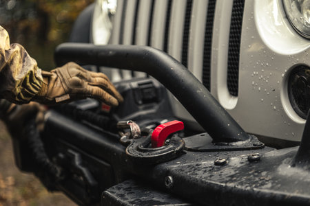 A Man Using SUV Electric Winch to Recover His Vehicle While Off Roading on a Muddy Road.の写真素材