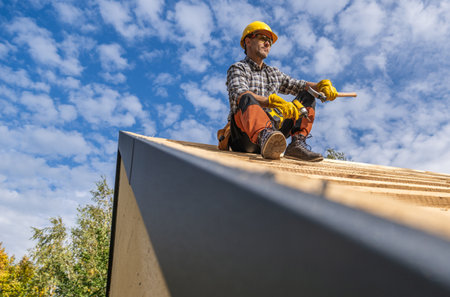 Roofing Construction Contractor Taking Short Break While Seating on a Top of the Roofの写真素材