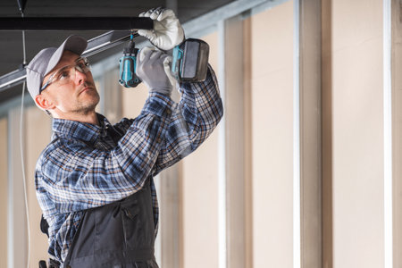 Caucasian Electrician Installing Suspended Lighting Elements Inside a Commercial Buildingの写真素材