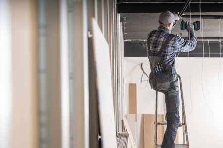 Caucasian Electrician Contractor in HIs 40s Installing Ceiling Lighting Elementsの写真素材
