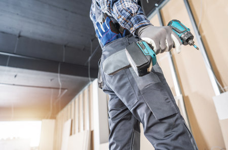 Construction Site Contractor Worker with a Drill Driver in His Hand. Interior Walls Building.の写真素材