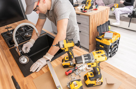 Caucasian man is diligently working on a table, surrounded by various power tools that he is using for his task.の写真素材