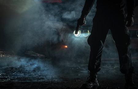 The silhouette of a person holding a handgun, standing in front of a car shrouded in smoke. Crime scene concept.の写真素材