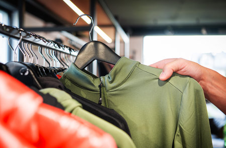 A shopper examines a green athletic top while browsing a rack of apparel in a contemporary retail...