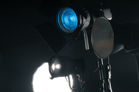 Multiple studio lights are arranged in a dark setting, showing different designs and color effects for an artistic shoot, illuminating the space creatively.の写真素材