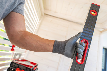 A worker in a gray shirt and gloves holds a leveling tool, focusing on achieving accuracy in a...