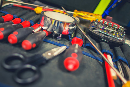 A collection of screwdrivers, scissors, and other tools is organized on a work surface, prepared for upcoming repair projects in a workshop setting.の写真素材