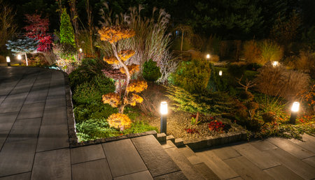 Warm lights illuminate the garden pathway, highlighting vibrant trees and manicured plants, creating...