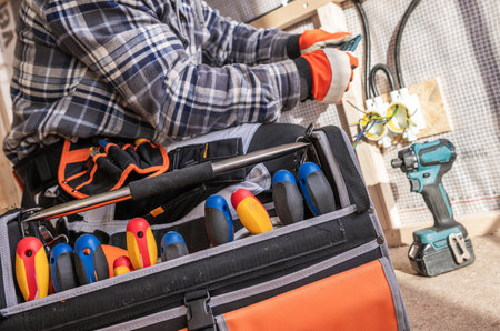 A technician is focused on fixing electrical wiring in a home. He uses various tools from his...