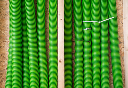 Green hoses are stacked and organized on wooden shelves in a storage area, showcasing a tidy collection of equipment. The setting highlights a focus on order and accessibility for future use.の写真素材