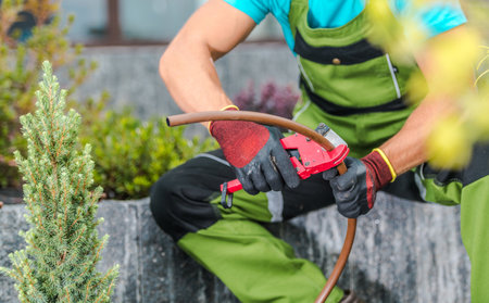 A gardener wearing green overalls and gloves is carefully adjusting equipment in a contemporary...