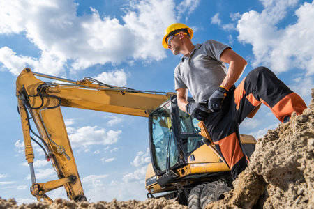 A construction worker in safety gear stands confidently next to an excavator, surveying the site as...