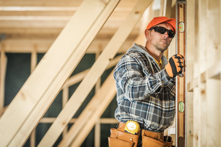 A skilled worker is measuring a wooden beam with a level tool, ensuring accuracy while building a...