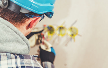 A skilled electrician works on installing electrical wiring in a building under construction....
