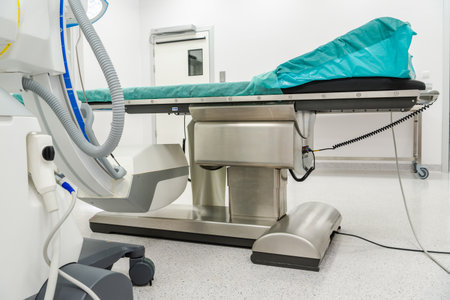 An organized hospital operating room features a clean examination table, medical equipment, and bright lighting typical for a surgical environment.の写真素材