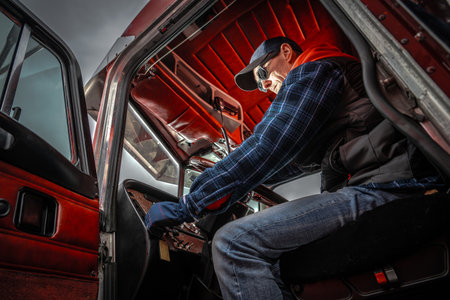 A truck driver adjusts controls inside a vintage truck's cab as gray clouds loom overhead, ready for the next leg of his trip.の写真素材