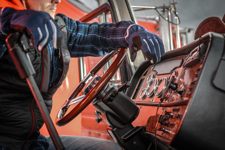 A truck driver grips the wheel with steering concentration in a brightly lit setting, showing dedication to their craft.の写真素材
