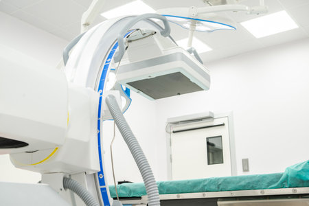 Medical tools are set up in an operating room with a green surface. A machine hangs above the space, ready for use.の写真素材