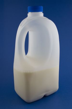 2 litre plastic milk bottle, half full, on blue backgroundの写真素材