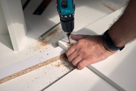 Man doing renovation work at home, drilling with a screwdriver. Group of repair tools on wooden white background.の写真素材
