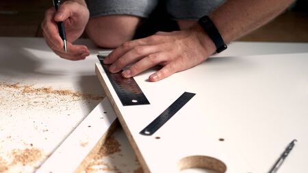 Man doing renovation work at home, drilling with a screwdriver. Group of repair tools on wooden...