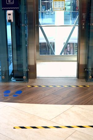 Warning black yellow stripe sign printed on ground before lift at the department store informing...