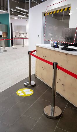 Yellow round sign printed on ground at supermarket cash desk register informing people to keep 2...