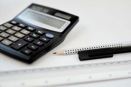 Close-up view accounting calculator white office desk table near pen, pencil, measuring scale and other office supplies.の写真素材