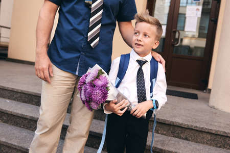 First day at elementary school. Father holding son hand. Pupil of primary school in uniform....