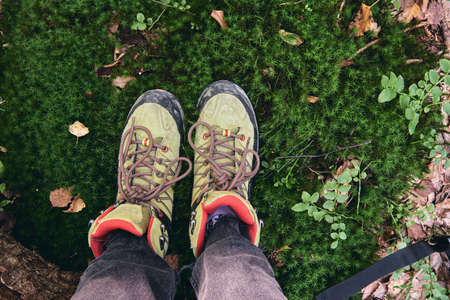 Hiking boots in outdoor action. Top View of Boot on the trail. Close-up Legs In Jeans And sport trekking shoes on rocky srones of Mountain river waterfall.の写真素材