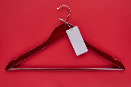 Wooden red hanger with black paper label isolated on red paper background. Seamless pattern mockup...