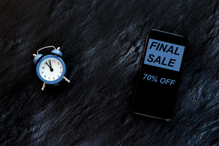Blue vintage alarm clock and smartphone isolated on dark background. Hot sale, final price, last...