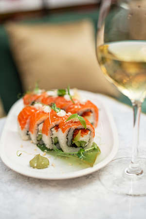 Sushi roll with salmon and avocado with glass of white wine. Japanese sushi set in restaurant menuの写真素材