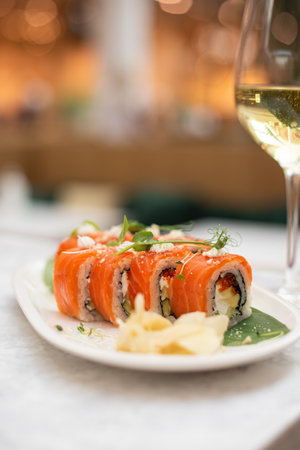 Sushi roll with salmon and avocado with glass of white wine. Japanese sushi set in restaurant menuの写真素材