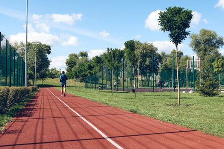 Athletic young man running. Exercising, stretching in the morning. Self care, wellness and sportの写真素材