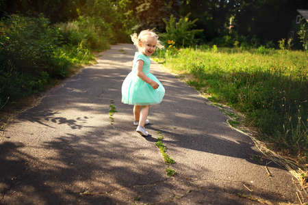 Portrait of a happy liitle blond girl close-up. 3 yaers caucasian todler girl smiling at outdoors walk. Kid dancing and shouting showing different emotions.の写真素材