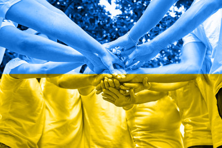 A diverse group of people on corporate teambuilding party. Stacking hands, partners standing...