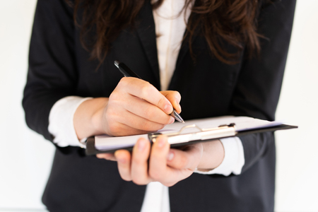 Business woman is writing something on a clipboardの写真素材