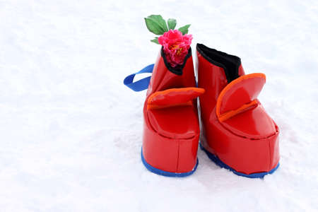 Big funny soft red shoes for competitions and entertainment in Shrovetide festivities. A pair of bright red boots on white snow.の写真素材