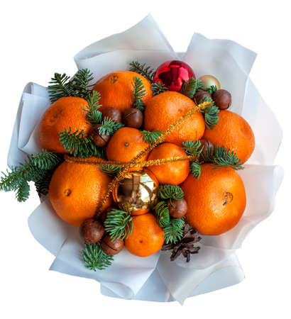 New years Christmas bouquet of oranges, tangerines, balls, macadamia nuts, spruce, cones on an isolated white background. A holiday bouquet. A gift for fans of healthy food. Holiday decor for table.の写真素材