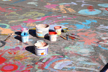 Group dirty used brushes and paint cans and pots on floor outdoor natural lightの写真素材