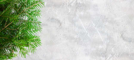 Christmas background with grey concrete structure and spruce branches without decoration on the right and empty space for text on the left. Top view of spruce branches on a gray stone surface. Bannerの写真素材
