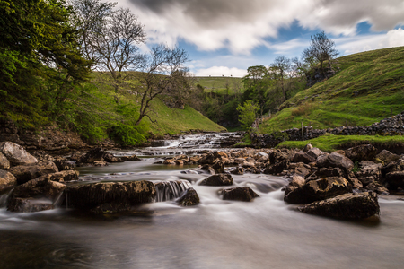 Water falling towards Thornton Force between the lush green hillsides.  Seen along the Ingleton waterfalls trail in North Yorkshire - captured as a long exposure with a ten stop ND filter.の写真素材