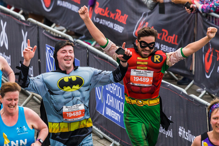Two men dressed as the characters Batman and Robin hold their hands in the air as they celebrate completing the 2017 Liverpool Rock n Roll half marathon on 28 May 2017.のeditorial素材